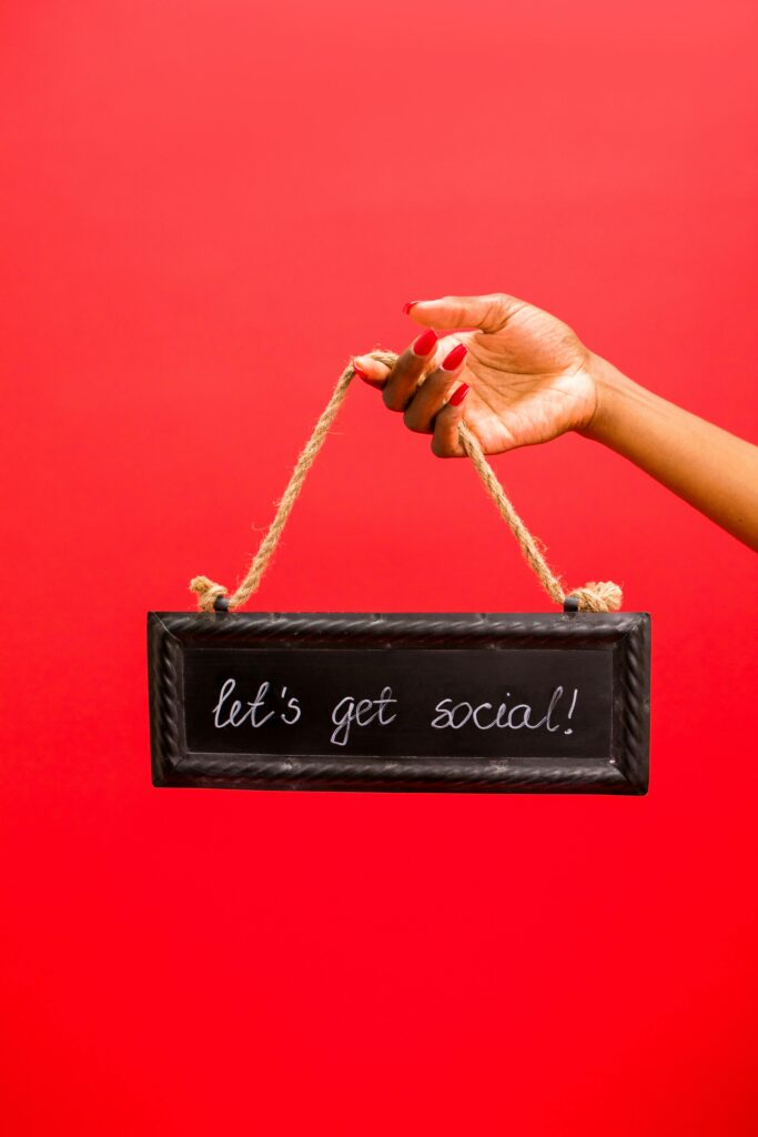 Hand holding a chalkboard sign with 'let's get social' text on a vibrant red background.